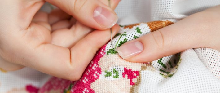 Woman hands doing cross-stitch. A close up of  embroidery.