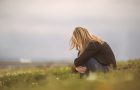 Side view of a despaired woman sitting curled up in nature.